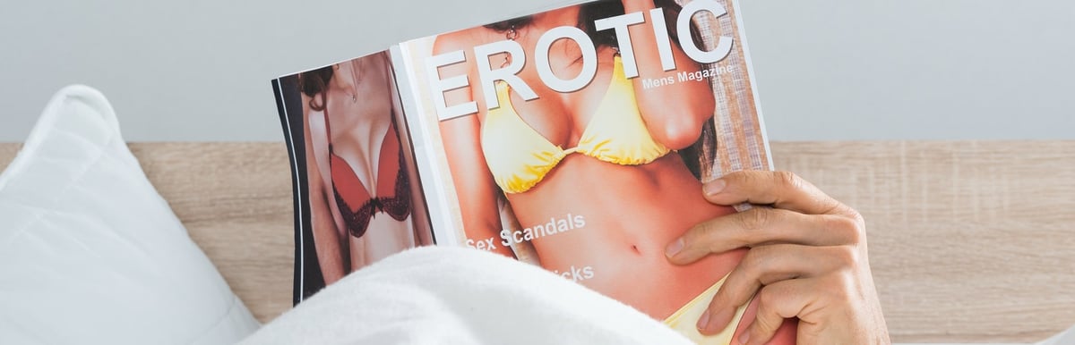 Ein Mann im Bett beim Lesen einer erotischen Zeitschrift