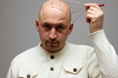 En skallig man ger sig själv en huvudmassage.