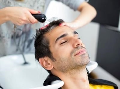 En mand får vasket sit hår hos en frisør.