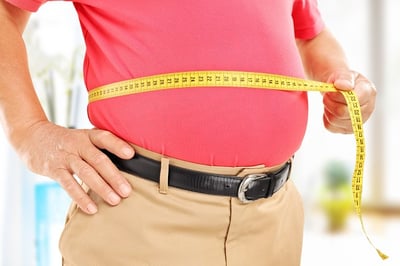 Ein übergewichtiger Mann misst sein Bauchvolumen