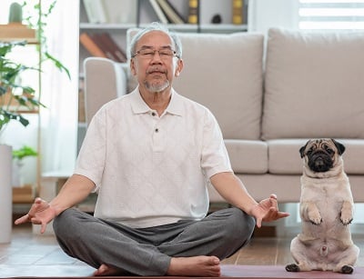Ein älterer Mann übt Yoga mit seinem Hund
