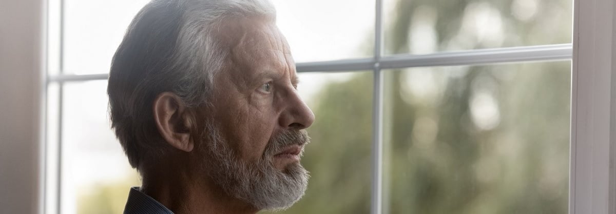 Um homem idoso a olhar pela janela