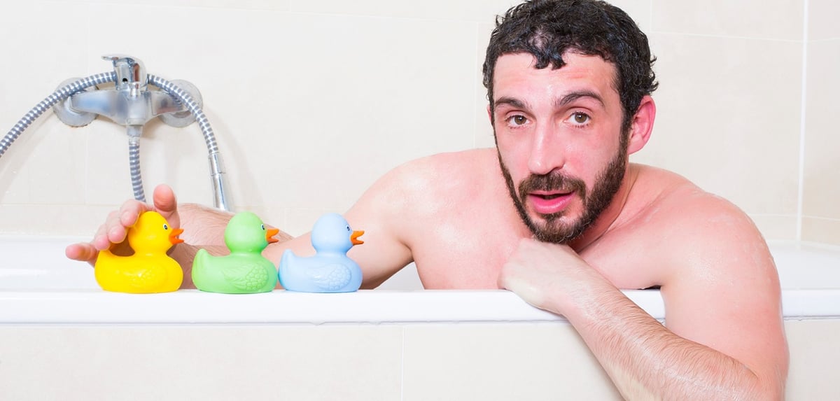 Ein Mann in der Badewanne mit drei Gummi-Enten