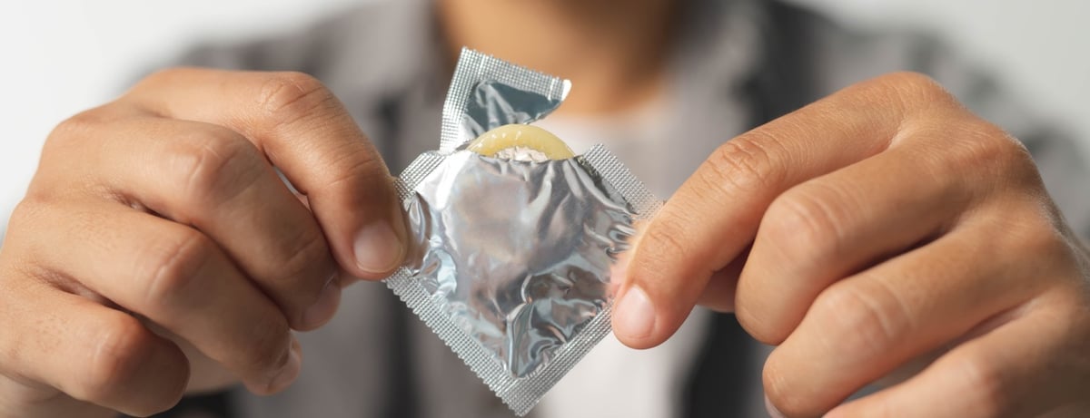 Ein Mann öffnet ein Kondom