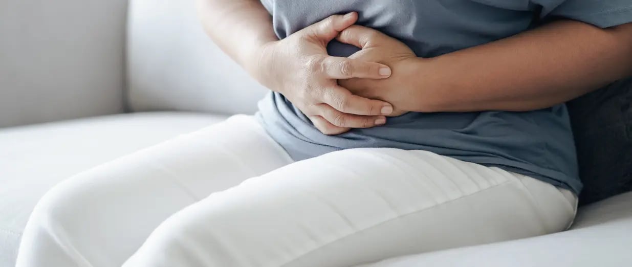 Person h&auml;lt sich wegen Bauchschmerzen den Unterbauch