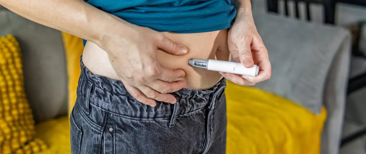 Person setzt sich mit einem Insulinpen eine Injektion in den Bauch