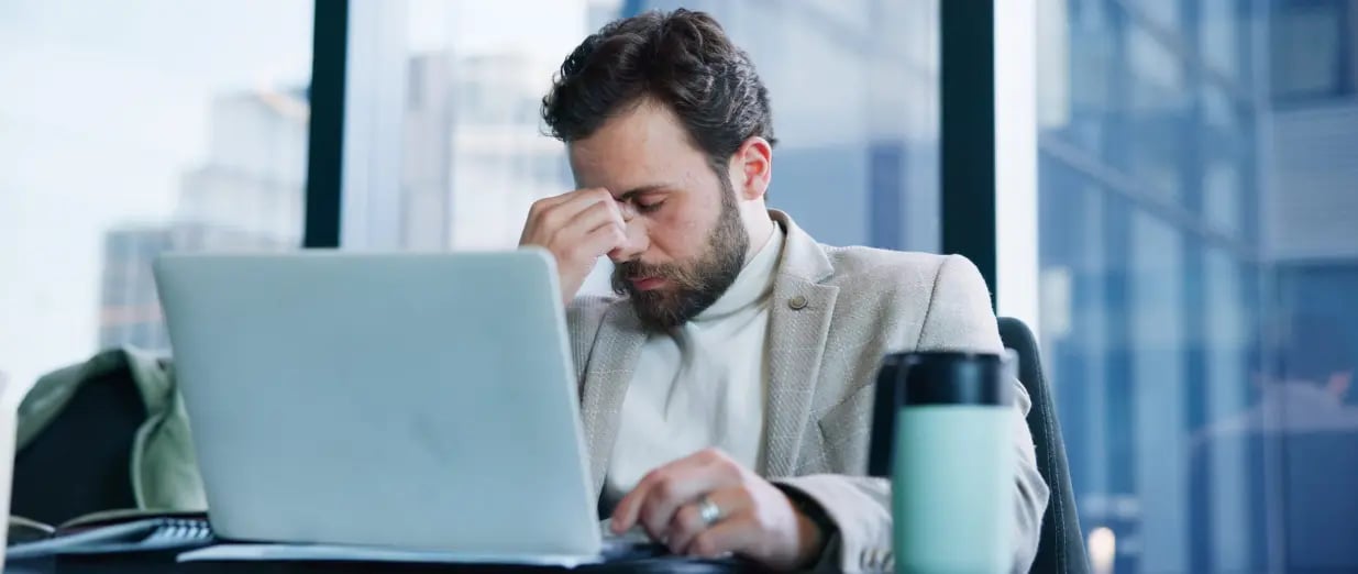 Homme stress&eacute; travaillant sur un ordinateur portable au bureau