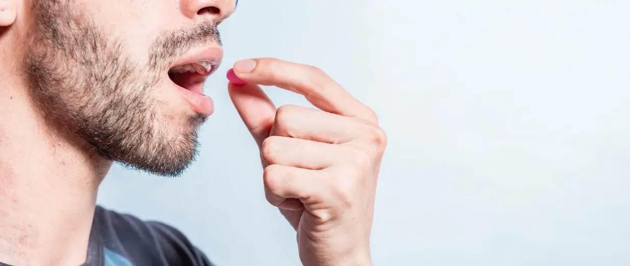 Homem tomando um comprimido