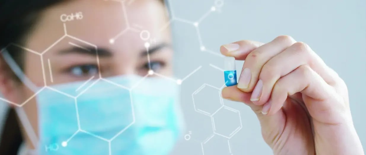 M&eacute;dica segurando c&aacute;psula com f&oacute;rmula qu&iacute;mica ao fundo
