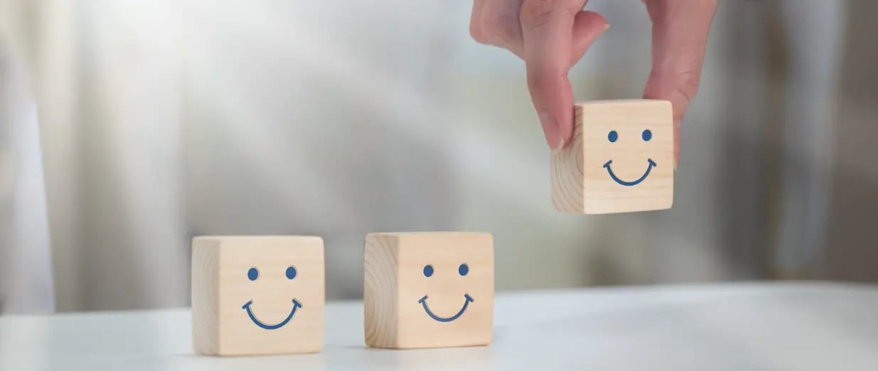 Blocos de madeira com rostos sorridentes, um sendo levantado