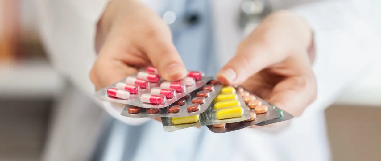 Mãos segurando diferentes comprimidos em blisters