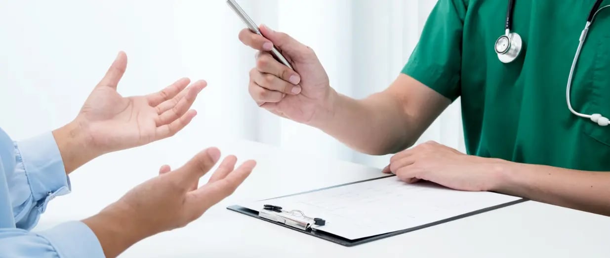 &Auml;rztin spricht mit Patient am Tisch