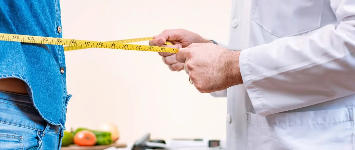 Arzt misst einem Patienten den Bauchumfang mit Ma&szlig;band