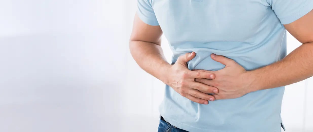 Ein Mann hält sich den Bauch vor Schmerzen