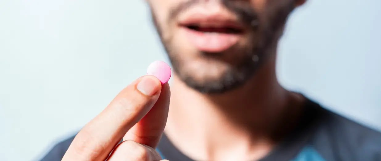 Enn Mann h&auml;lt eine rosa Tablette in der Hand