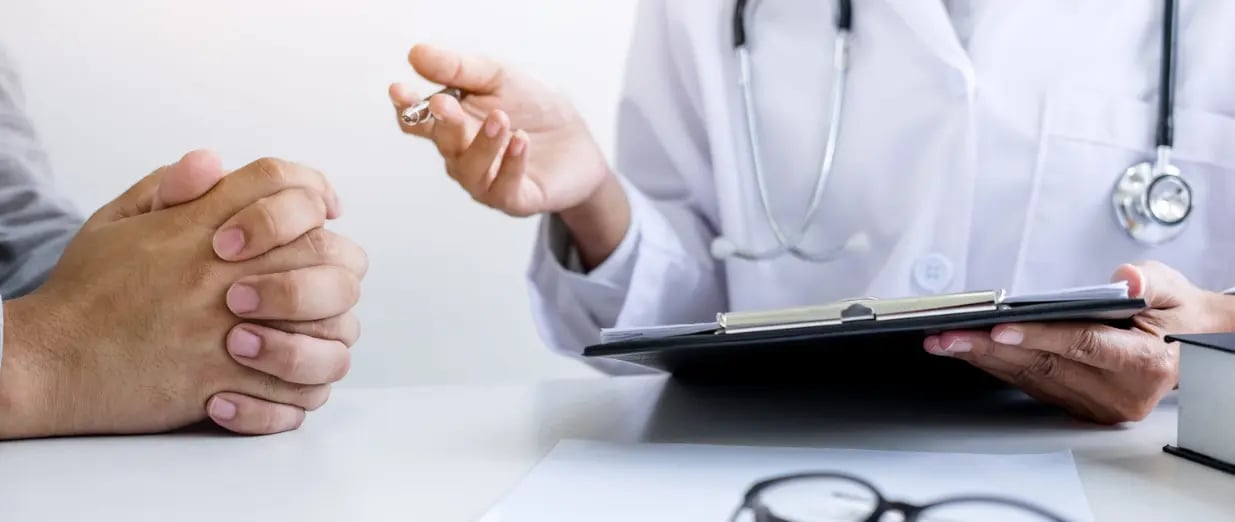 Doctor filling out a medical history form while consulting a patient and recommending treatment methods