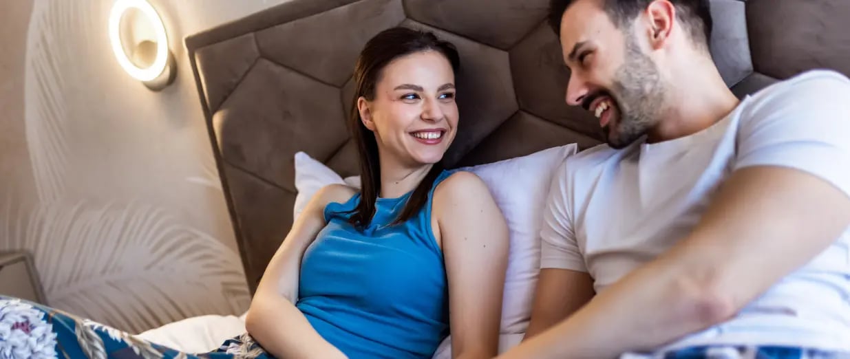 Ein liebenswertes Paar h&auml;lt im Bett H&auml;ndchen und unterh&auml;lt sich