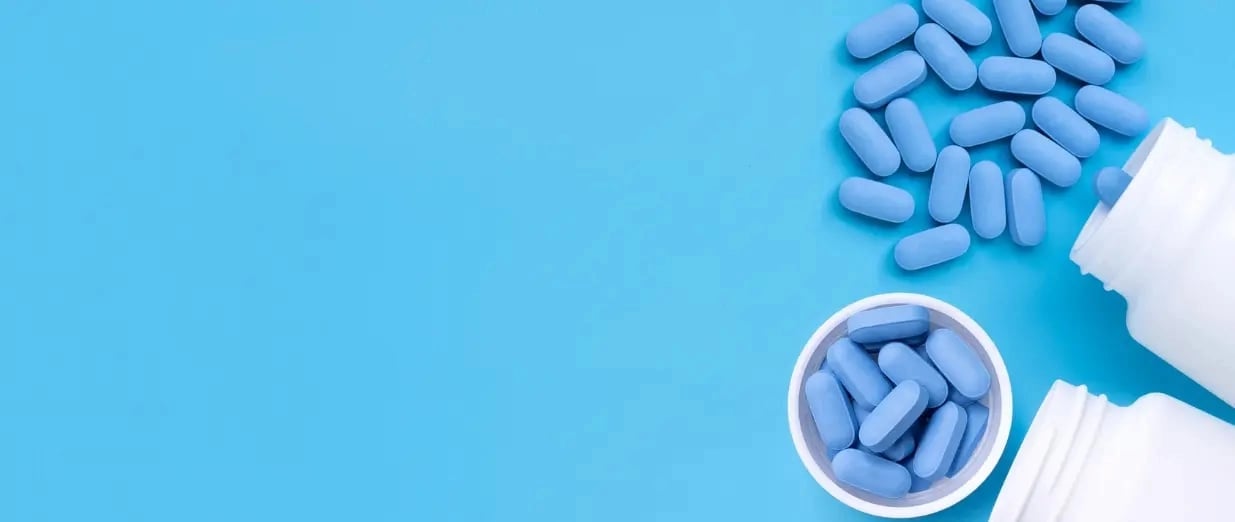 Blaue Tabletten, die neben einem geöffneten Behälter verstreut liegen