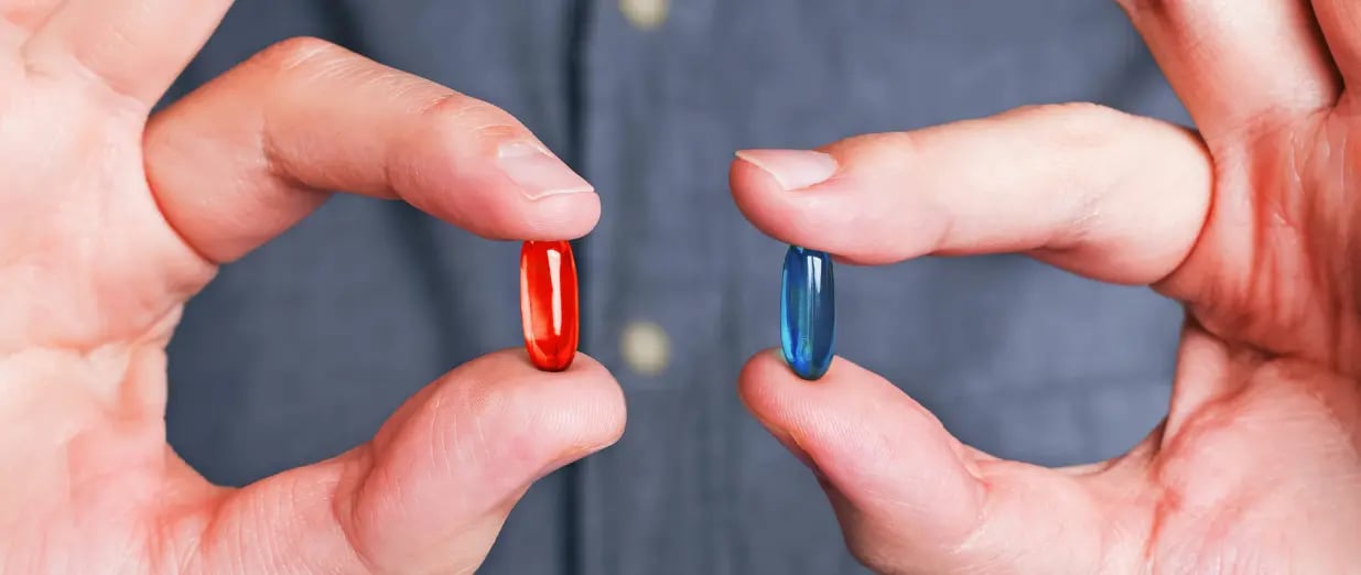 A man holding red and blue pills in his hands