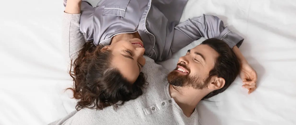 L&auml;chelndes Paar entspannt im Bett