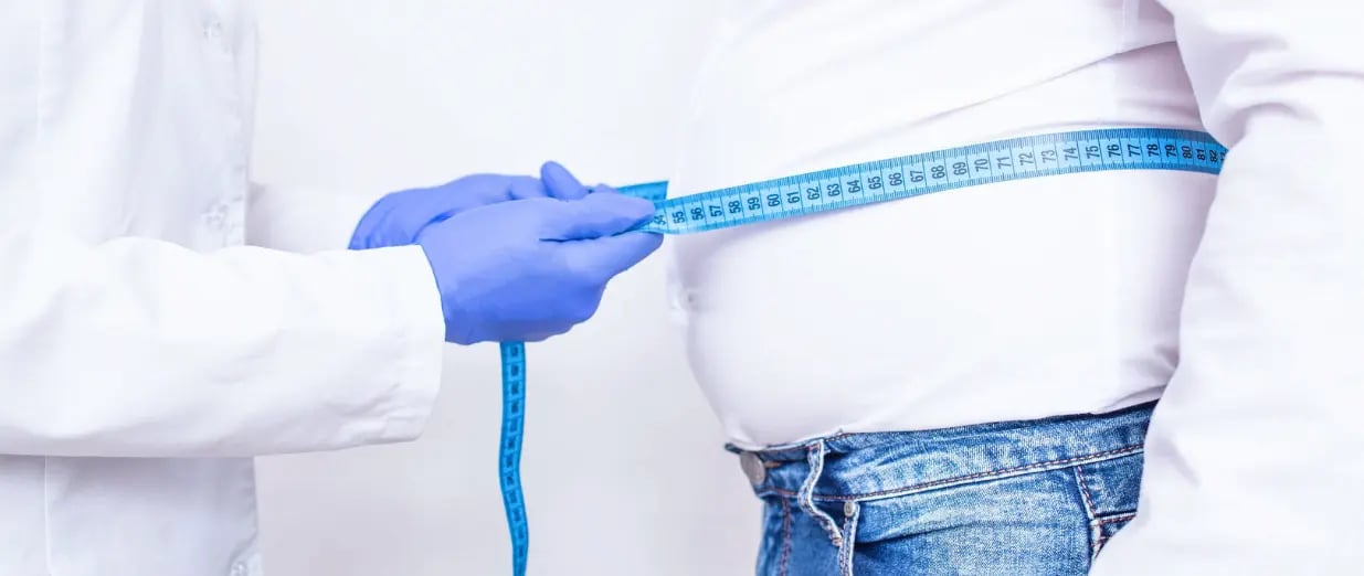 Eine Person wird mit einem Ma&szlig;band am Bauch gemessen