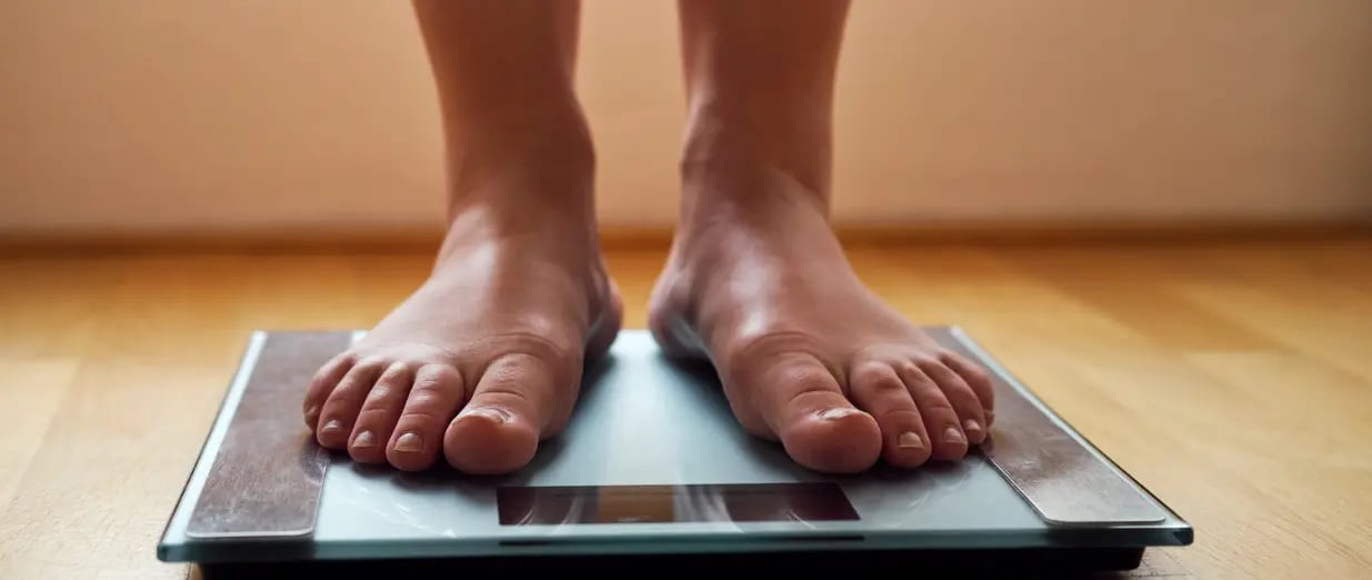 Eine Person steht barfuß auf einer Waage