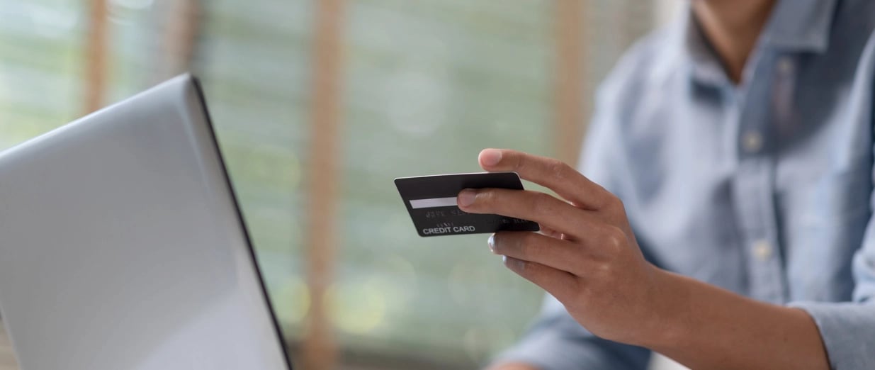 Person holding a credit card while shopping online on a laptop computer