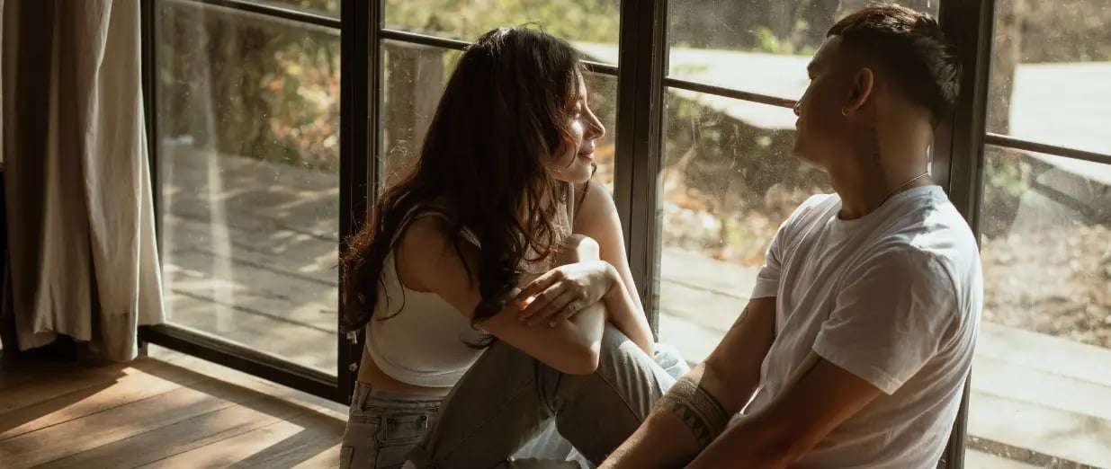 Casal conversando sentado junto &agrave; janela