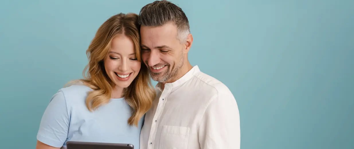 Paar schaut l&auml;chelnd auf ein Tablet