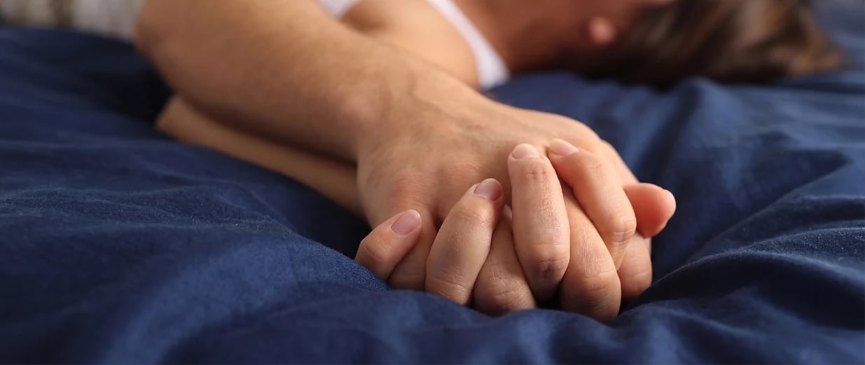 Paar h&auml;lt H&auml;nde im Bett