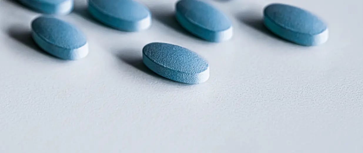 Comprim&eacute;s de Viagra bleus sur une surface blanche
