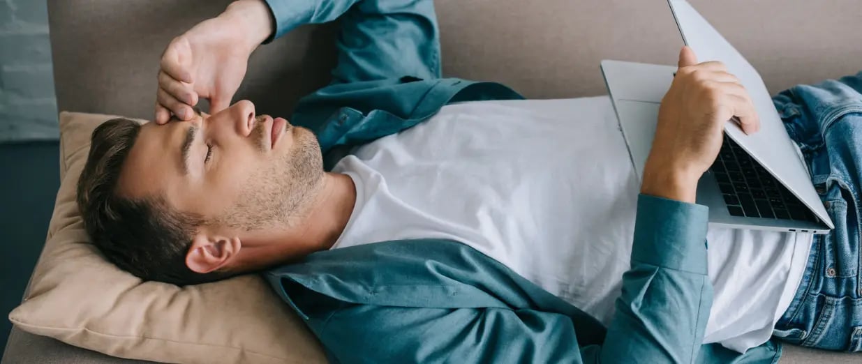 Mann liegt auf dem Sofa mit einem Laptop