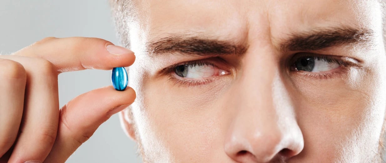 a guy suspiciously looking at a blue pill