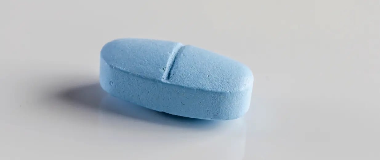 A blue pill on a grey background