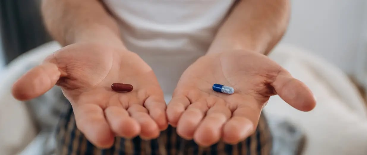 Man holding two different pills in each hand
