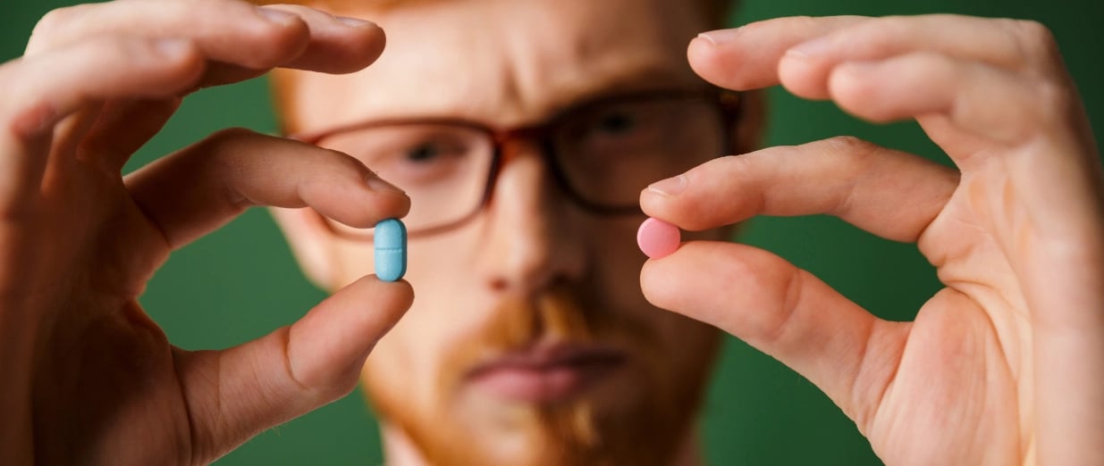A man holding 2 tablets in his hand and comparing