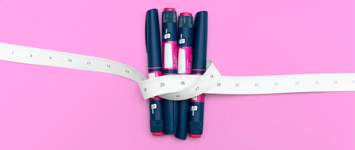 Abnehmspritzen und Ma&szlig;band auf rosa Hintergrund
