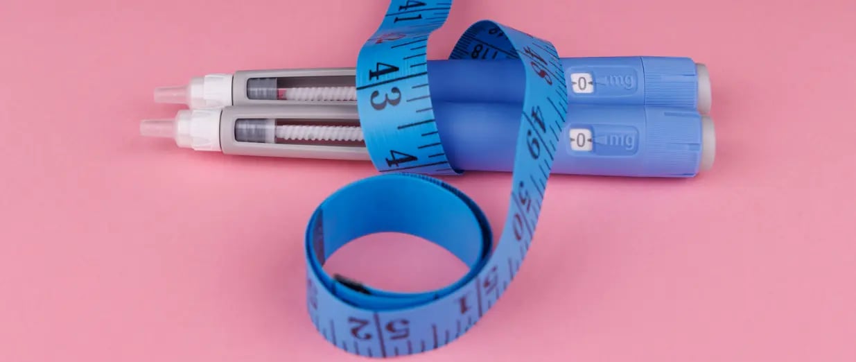 Abnehmspritzen mit Ma&szlig;band auf rosa Hintergrund