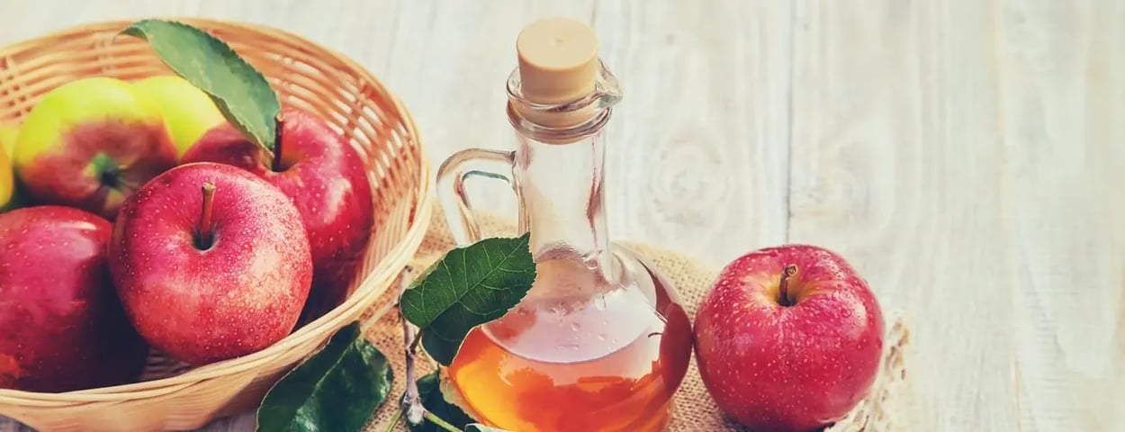 Eine Flasche Apfelessig mit einer Schüssel frischer Äpfel