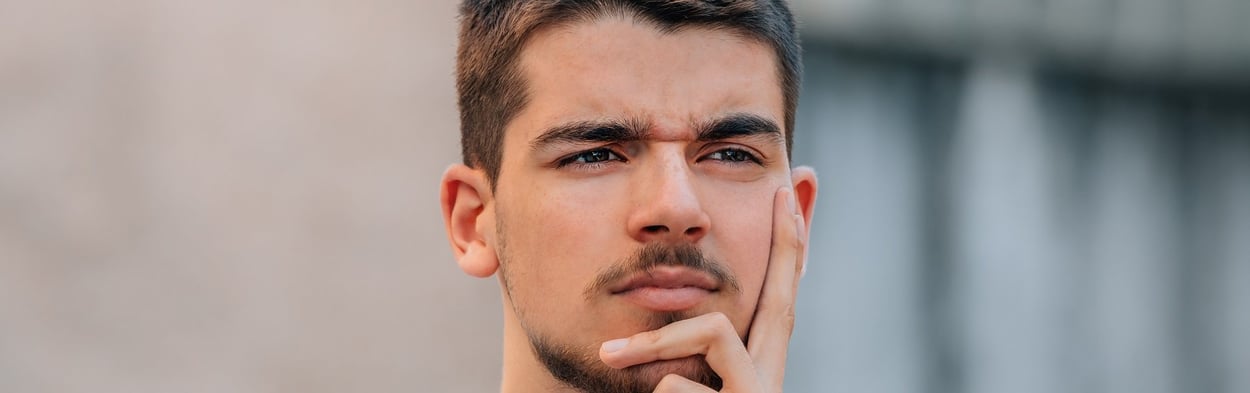 Junger Mann, der mit einer störenden Frage beschäftigt aussieht