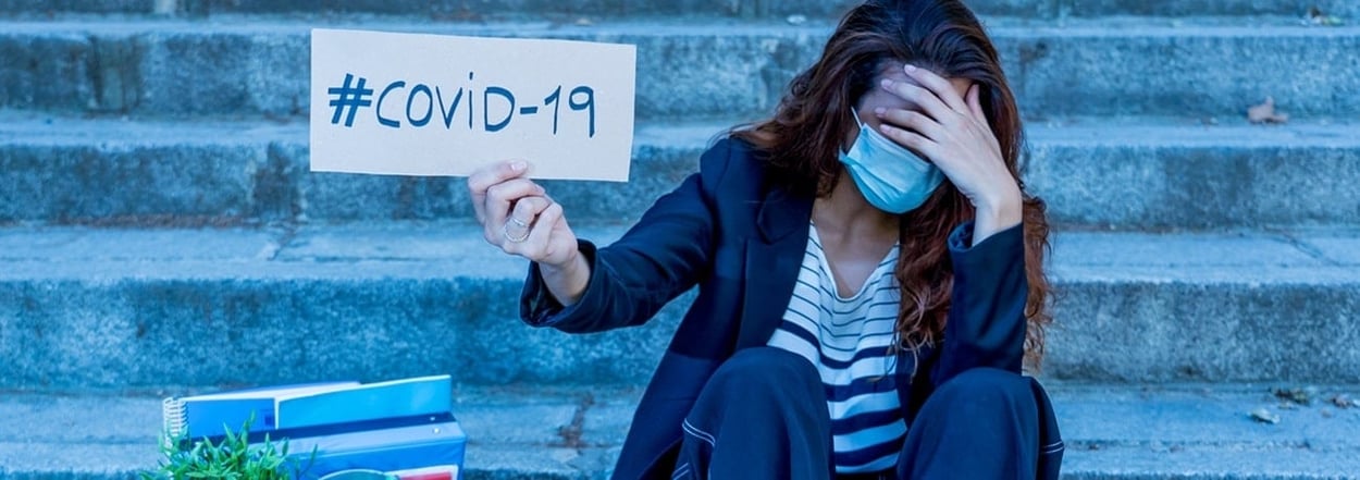 Traurige Frau mit Gesichtsmaske, die eine Kiste mit Personal und einem COVID-19-Schild in der Hand hält