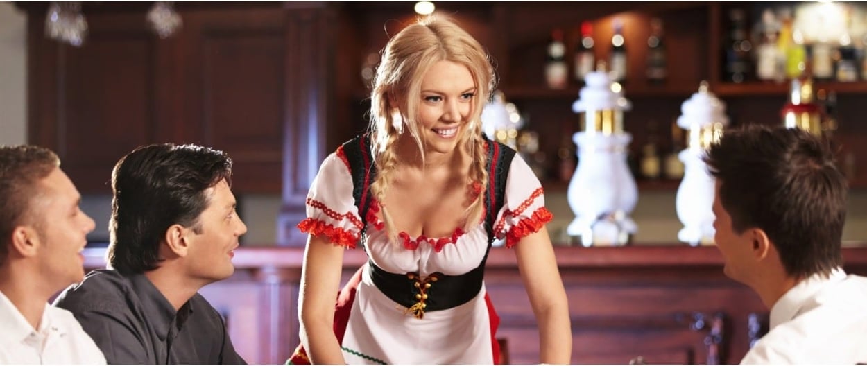 Eine junge Frau in traditioneller Tracht serviert Bier auf einer Oktoberfest-Party