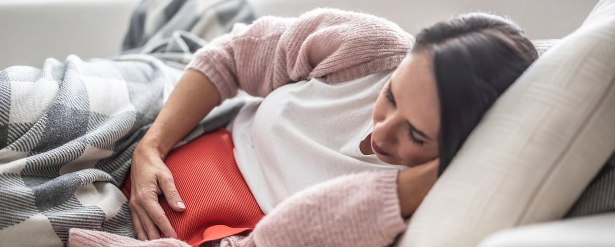 Eine kranke Frau liegt auf einem Sofa.