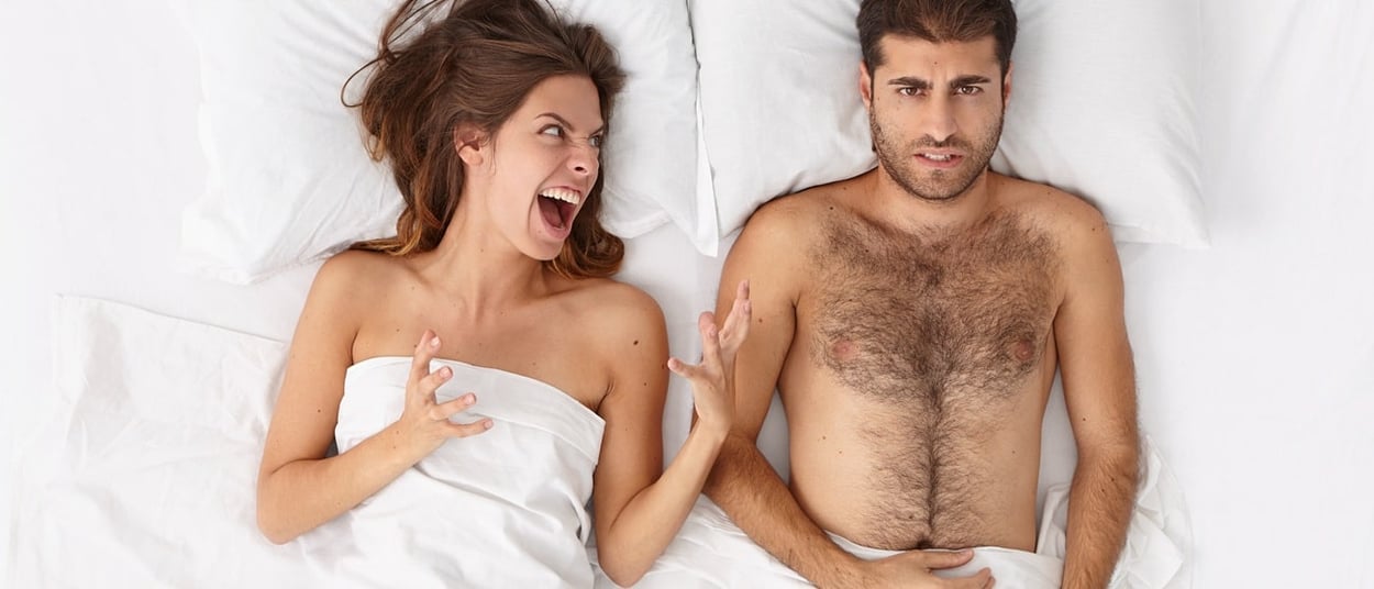 Eine verärgerte Frau streitet sich mit ihrem Mann im Bett.