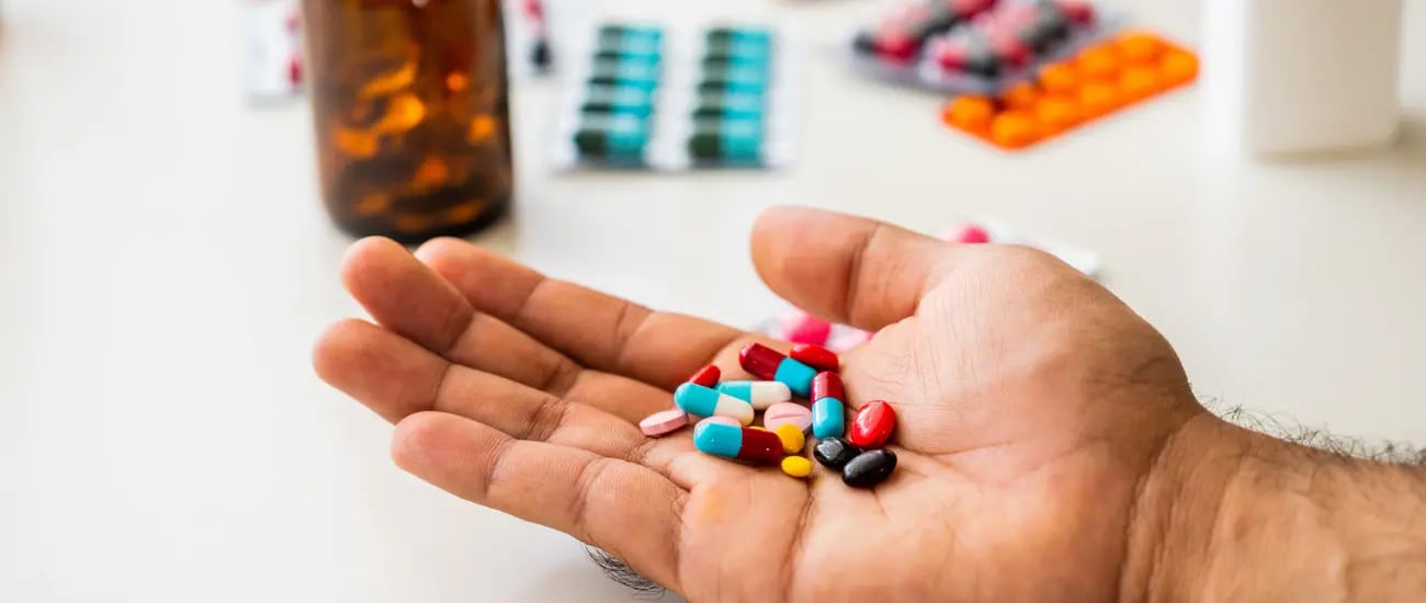 Ein Mann h&auml;lt eine Handvoll Tabletten in seinen H&auml;nden