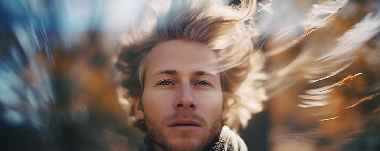 Porträt eines gut aussehenden jungen Mannes mit fliegenden blonden Haaren im Herbstpark