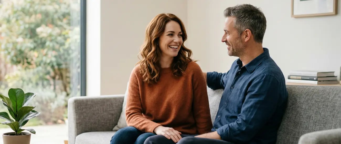 L&auml;chelndes Paar sitzt entspannt auf dem Sofa und schaut sich an