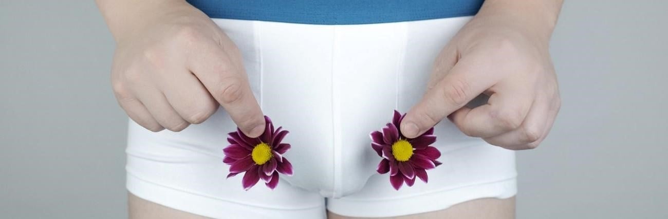 Man i vita byxor håller blommor som en symbol för testikelcancer