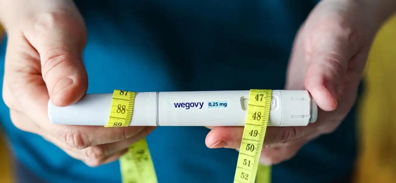 Mann h&auml;lt Wegovy-Injektionspen mit Ma&szlig;band zur Gewichtsreduktion