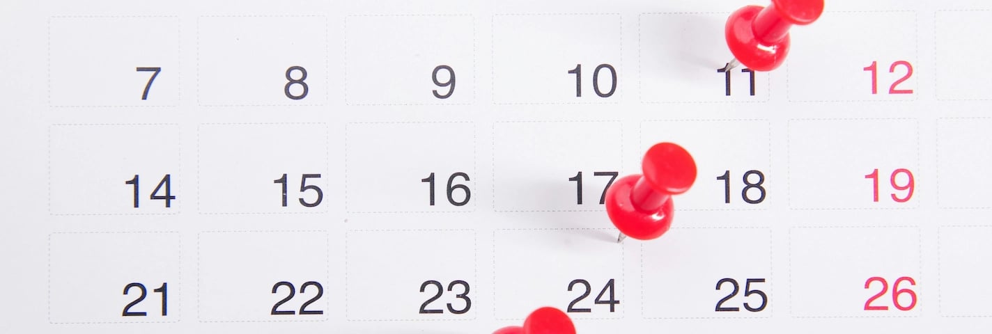 Calendário com tachinhas vermelhas marcando datas